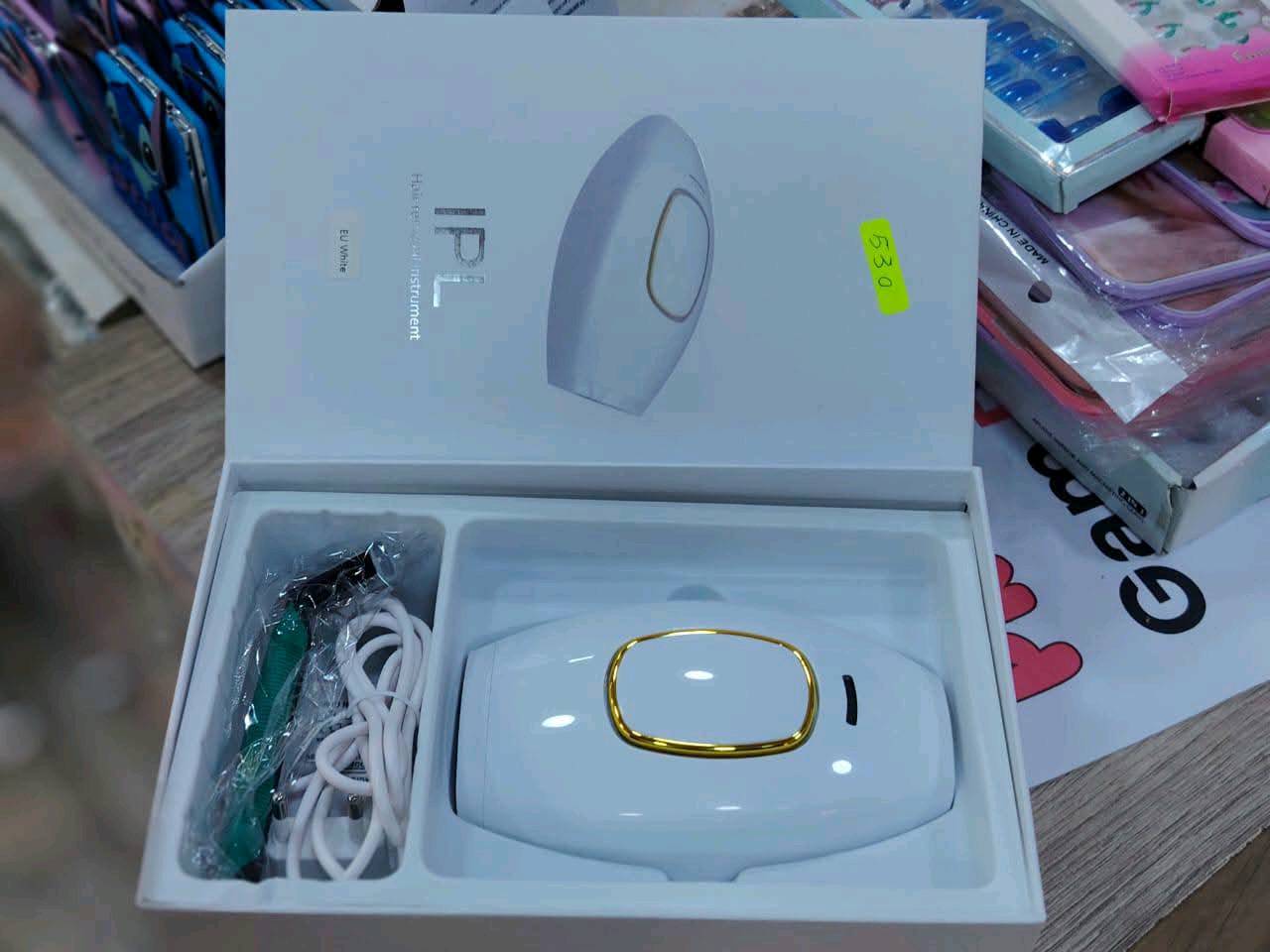 جهاز إزالة الشعر بالنبض الضوئي المكثف (IPL) المنزلي، ويأتي معه ملحقات تشمل شاحن كهربائي، ونظارة لحماية العينين، وموس حلاقة صغير.مكونات المجموعة: تتضمن الجهاز الرئيسي بلونه الأبيض والإطار الذهبي، شاحن الطاقة، نظارة واقية سوداء، وأداة حلاقة تحضيرية.طريقة العمل: يعتمد الجهاز على تقنية الـ IPL لإصدار ومضات ضوئية تخترق الجلد وتضعف بصيلات الشعر تدريجياً لتقليل نموه على المدى الطويل.