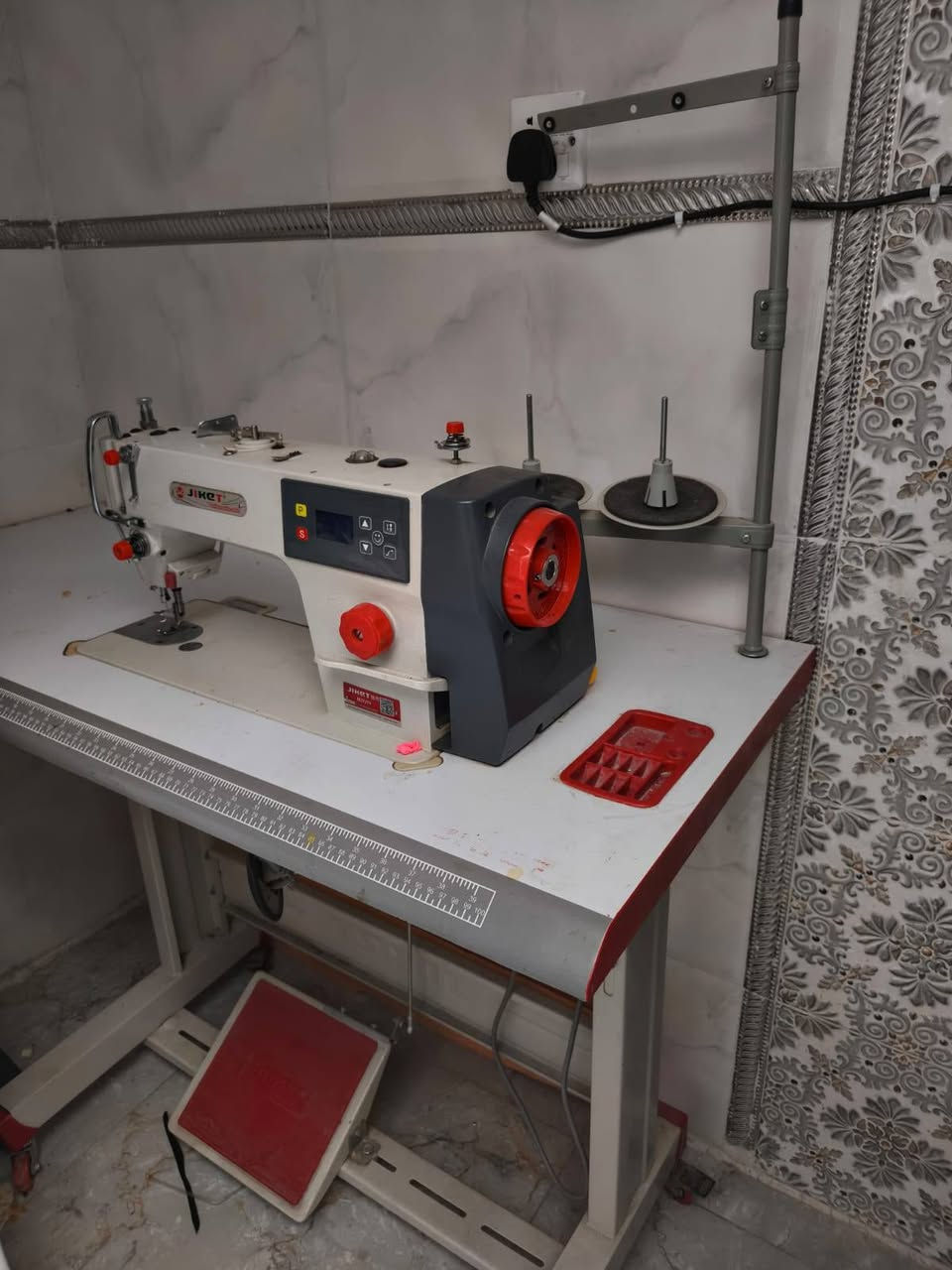 السلام عليكم 

هذه ماكينة خياطة صناعية درزة (Lockstitch) من شركة جاكيت (JIKET) موديل M2F (أو فئة M2 المتطورة بمحرك مباشر وسحب سريع).

⚙️ المواصفات والميزات الرئيسية:
محرك مباشر مدمج (Direct Drive): يوفر تشغيلاً صامتاً (كاتم للصوت) مع توفير كبير في استهلاك الطاقة مقارنة بالمحركات الخارجية التقليدية.

لوحة تحكم رقمية (شاشة رقمية): تتيح للمستخدم ضبط وتعديل خيارات التشغيل بسهولة، مثل التحكم بالسرعة (زيادة أو تقليل السرعة لتناسب مهارة الخياط ونوع القماش)

.منظم طول الغرزة الميكانيكي: البكرة الحمراء الكبيرة في الواجهة مخصصة لتعديل طول مسافة الغرزة بدقة.إضاءة LED مدمجة: مصباح مدمج عند منطقة الإبرة لتسهيل الرؤية وتخفيف إجهاد العين أثناء العمل

.نظام تزييت أوتوماتيكي: مضخة زيت داخلية تضمن تشحيم كافة الأجزاء الميكانيكية تلقائياً لتقليل الاحتكاك وزيادة العمر الافتراضي للماكينة.

استعمال قليل جداً السعر (350 الف) وبيه مجال قليل 
عنواني بغداد الحسينية مدخل الحمل 
*********** واتساب او تصال
