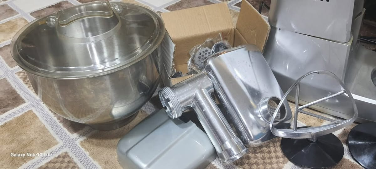 ست البيت ماركه  بلون فضي.تتميز بوعاء سعة كبيرة تتراوح عادة بين 6 إلى 8 لترات.تحتوي على محرك قوي يصل إلى 1000 واط أو أكثر في بعض الموديلات.تتضمن مفتاح تحكم للسرعة يحتوي على وضع النبض (Pulse) 

1. الهيكل الرئيسي والأبريق
 الوحدة الرئيسية (المحرك): الهيكل الأساسي ذو اللون الفضي/الرمادي.
 إبريق الخلاط الزجاجي: مركب في الأعلى مع الغطاء الخاص به (للعصائر والخلط).
 مطحنة صغيرة (مفرمة بهارات/قهوة): ممركبة في القاعدة المخصصة لها على اليمين.
2. ملحقات العجن والخلط
 وعاء العجن: وعاء كبير من الاستانلس ستيل مزود بغطاء بلاستيكي لمنع الطرطشة.
 مضرب السلك (المخفقة): لخفق البيض والكريمة.
 خطاف العجين: لخلط وعجن العجائن الثقيلة.
 مضرب الخلط (على شكل حرف K / الورقة): لخلط المزيج المتوسط مثل الكيك والمخبوزات.
3. ملحقات مفرمة اللحم
 رأس مفرمة اللحم: هيكل معدني يتم تركيبه على الجهاز.
 صينية التغذية العلويّة: لوضع قطع اللحم قبل فرسها.
 أنبوب/كباس الضغط: موجود داخل الكرتون الصغير المرفق لضغط الأطعمة داخل المفرمة.

استخدام قلليل سعرها 160 

***********
