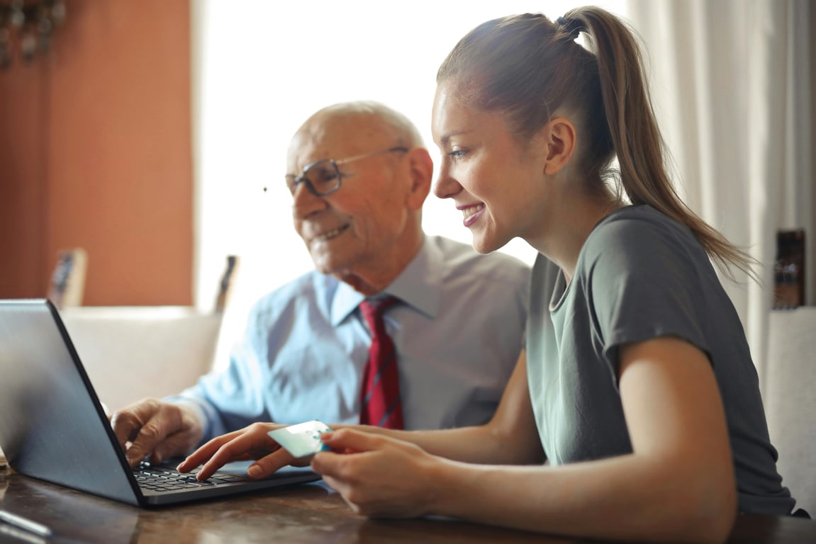 woman sitting at table with elderly man at a computer