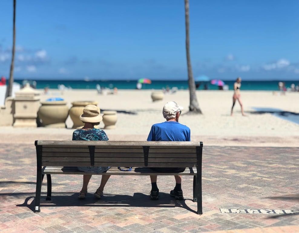 elderly couple sitting on a bench by the beach