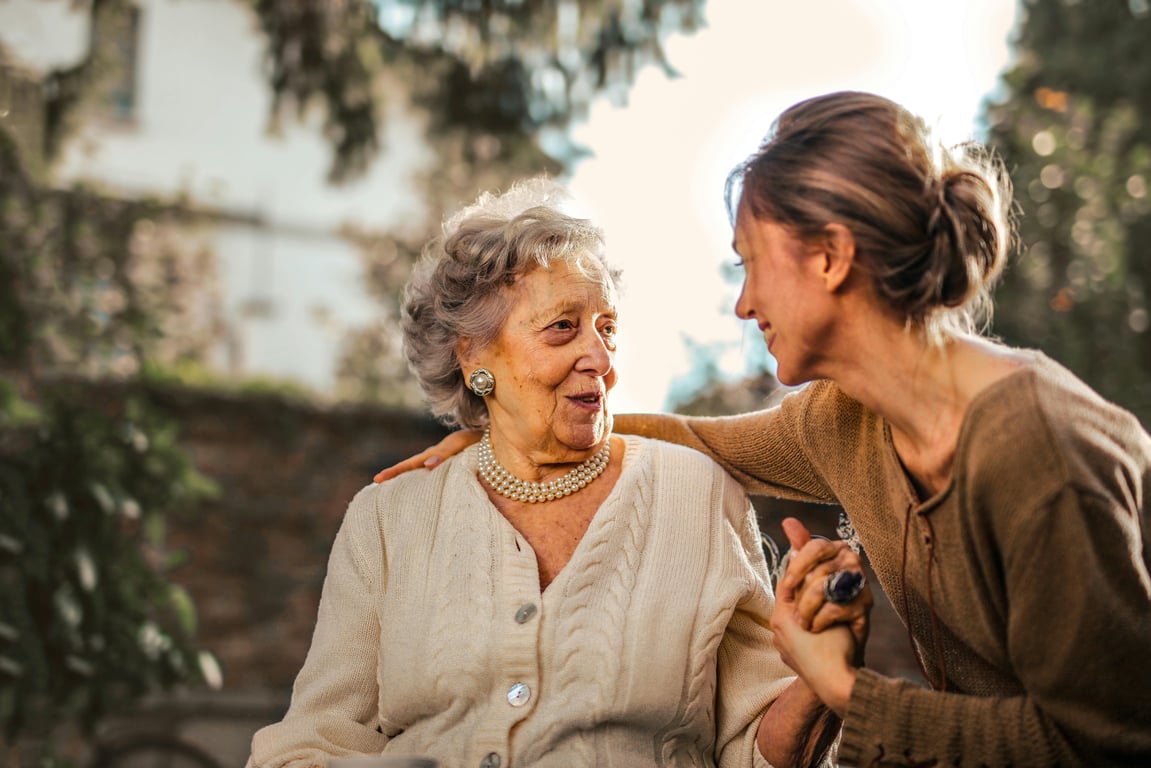 young and elderly woman holding hands