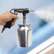 Hand holding air sandblasting gun in action spraying abrasive media