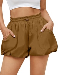 Woman wearing brown high-waisted bubble shorts with hands in pockets showing fit