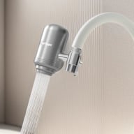 Stainless steel faucet filter attached to white kitchen faucet with water flowing