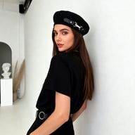 Woman wearing black leather beret cap in bright studio environment