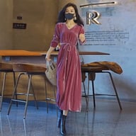 Woman wearing rose pink velvet dress in cafe, loose fit and V-neckline visible