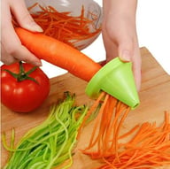 Carrot being spiralized into noodles with green handheld spiralizer tool