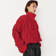 Red pleated stand-collar coat on white background displaying full design