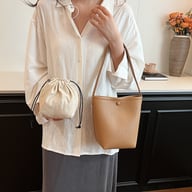 Woman holding tan pebbled leather bucket bag with drawstring pouch included