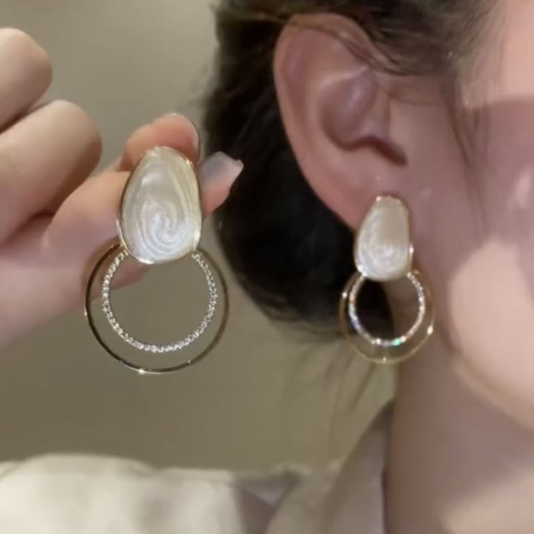 Hand holding sparkly geometric loop drop earring, premium zircon design detail