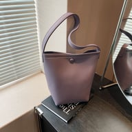 Purple pebbled leather bucket bag displayed on table surface