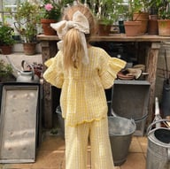 Back view of girl in yellow plaid Nordic outfit with large decorative bow