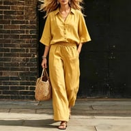 Woman in yellow linen shirt and loose pants set with woven accessory walking