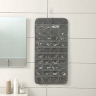 Gray hanging jewelry organizer mounted on bathroom wall with accessories organized