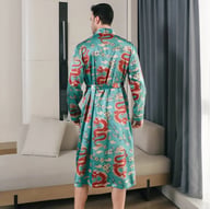 Man relaxing in living room wearing teal ice-silk dragon print long-sleeve nightgown