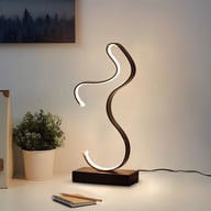 Contemporary curved LED desk lamp illuminating workspace with USB power supply