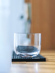 Empty crystal whisky glass on black bar mat showing clarity and design
