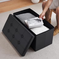 Open black foldable storage ottoman with items being placed inside