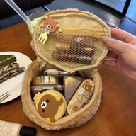 Cute bear makeup bag filled with cosmetics and brushes on wooden vanity table