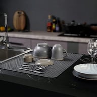 Silicone drying mat with dishes and pot placement near kitchen sink area