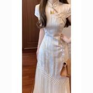 Full-length view of cream cheongsam dress with asymmetrical pleated hem
