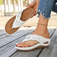 Woman holding white floral wedge sandal showing comfort slip-on design