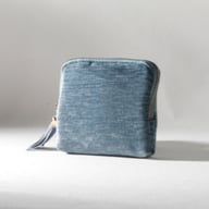 Blue velvet zippered cosmetic bag with tassel on white background