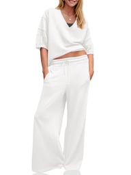 Woman wearing white women's wide leg tracksuit set with V-neck top