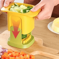 Yellow and green manual vegetable chopper dicing cucumber on wooden cutting board