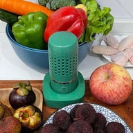 Green portable fruit and vegetable purifier surrounded by fresh strawberries and produce