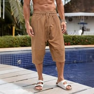 Man wearing brown linen capri pants by pool in summer heat