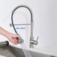 Person using pull-out spray head to rinse large pot in kitchen sink