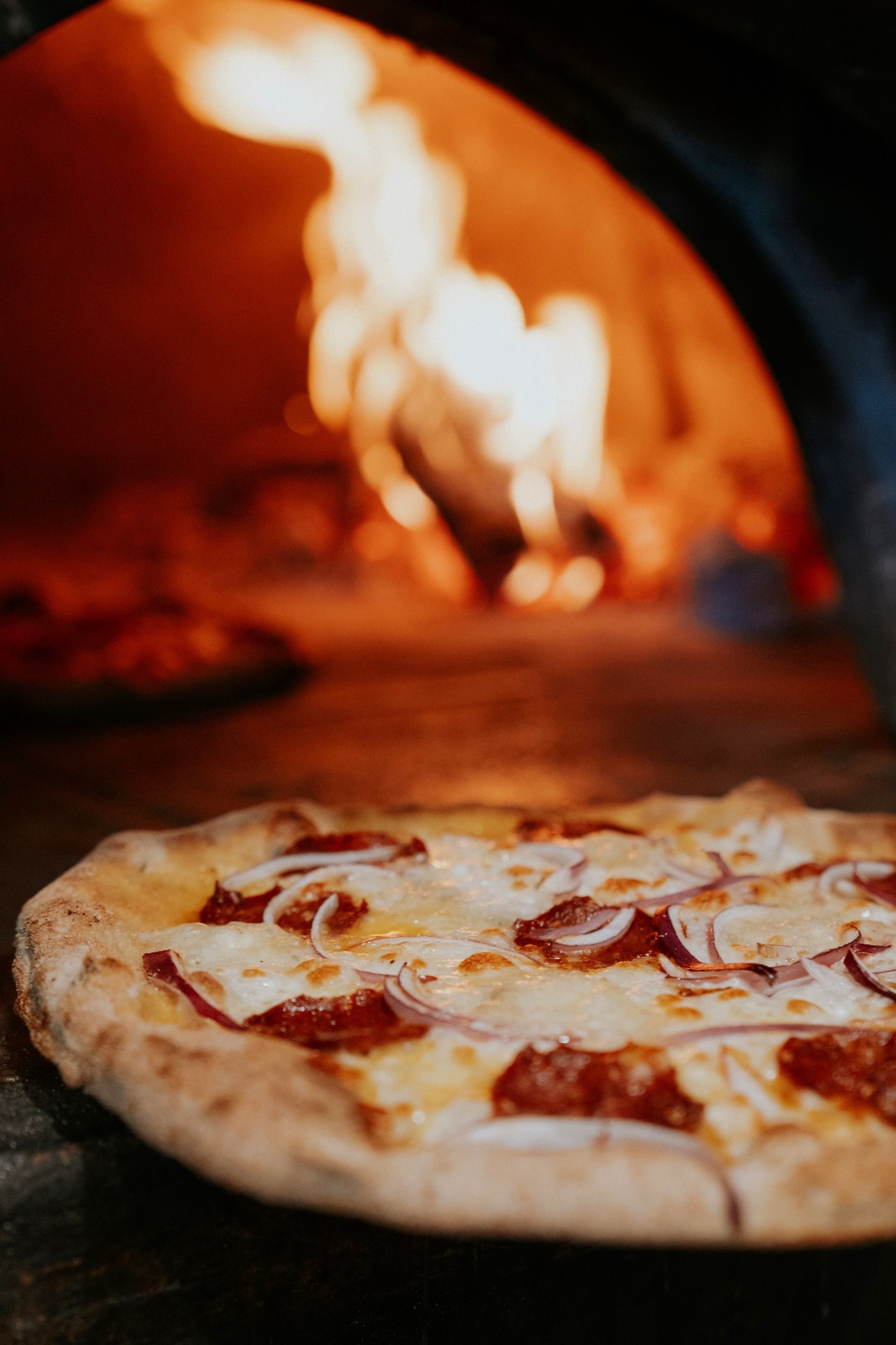A pizza at the mouth of the woodfire oven