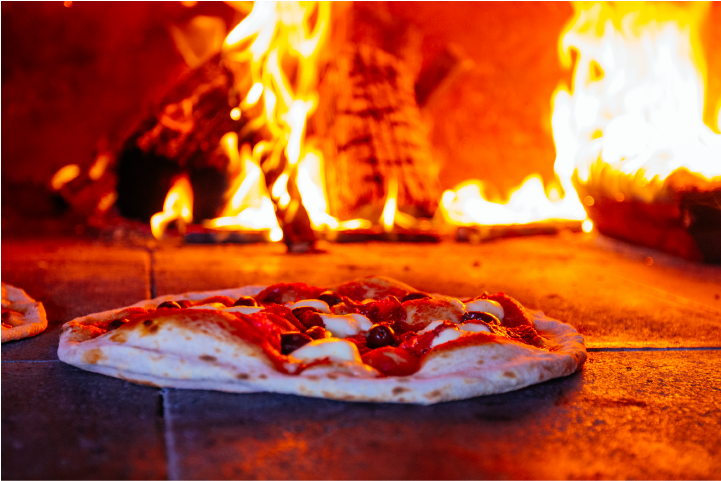 A pizza in front of the flames