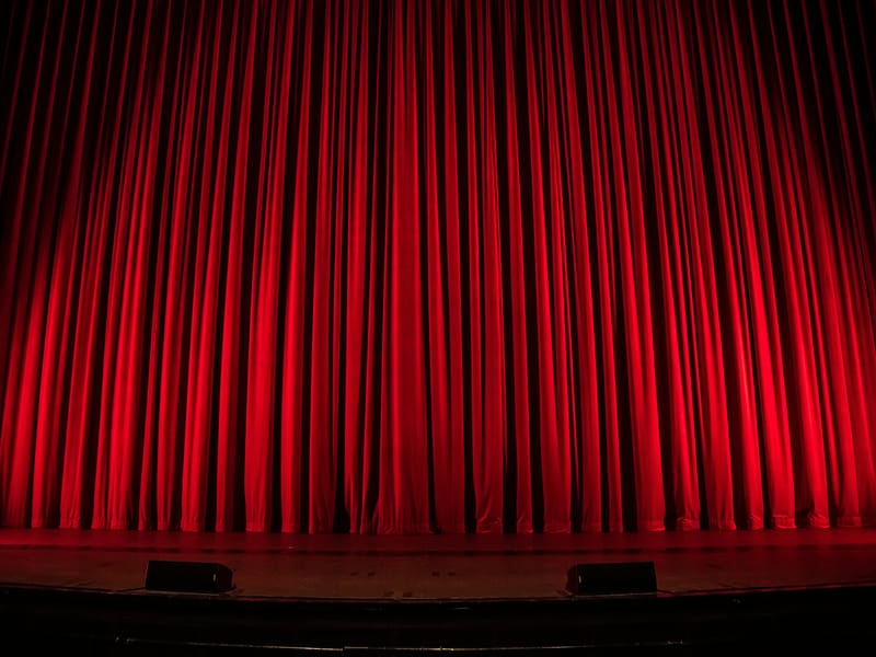 Illustrative image: a red velvet theater curtain lit from above