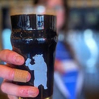 A pint of dark beer in a 105 West Brewing bear glass