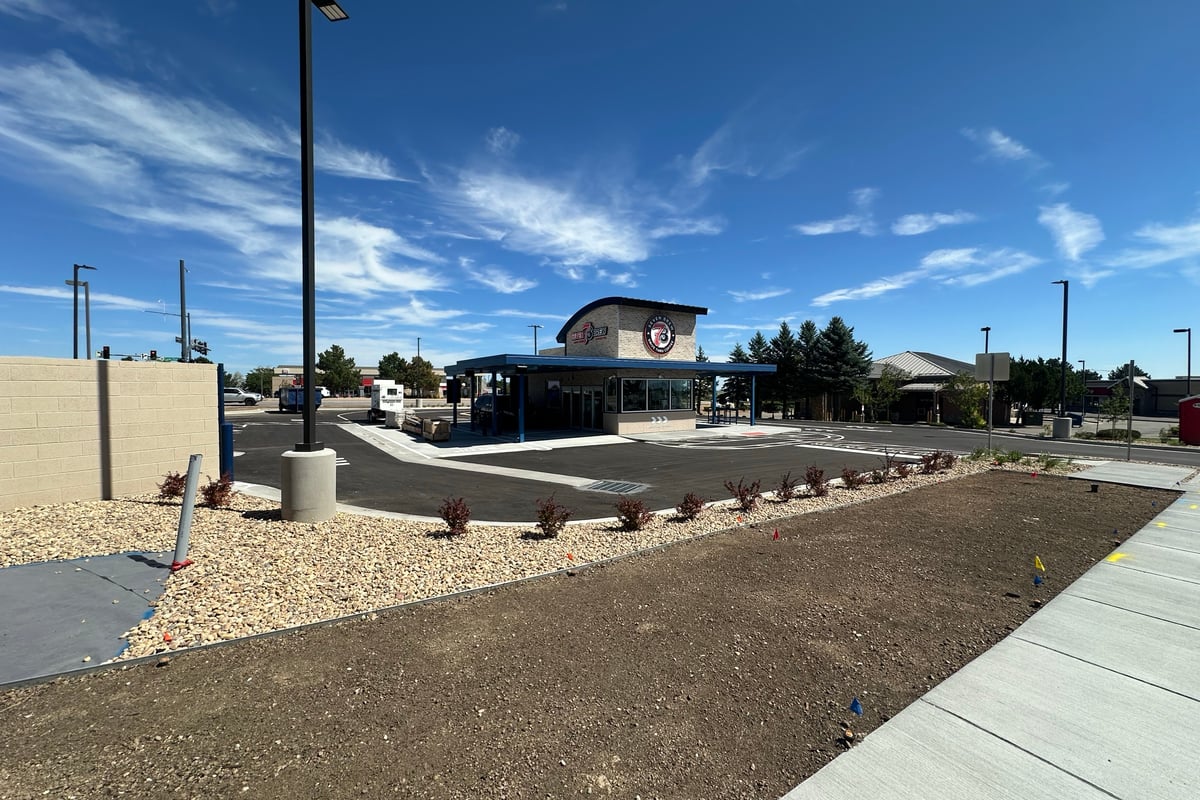 The new 7 Brew drive-thru coffee building on Castle Pines Parkway at Debbie Lane under a blue sky