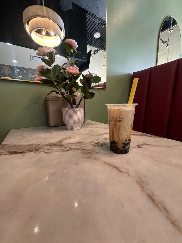 Pearl milk tea with a yellow straw at Badger & Bloom Boba