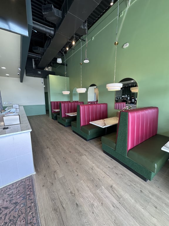 Inside Badger & Bloom Boba — pink booths, green walls, and pendant lights at the Outlets at Castle Rock