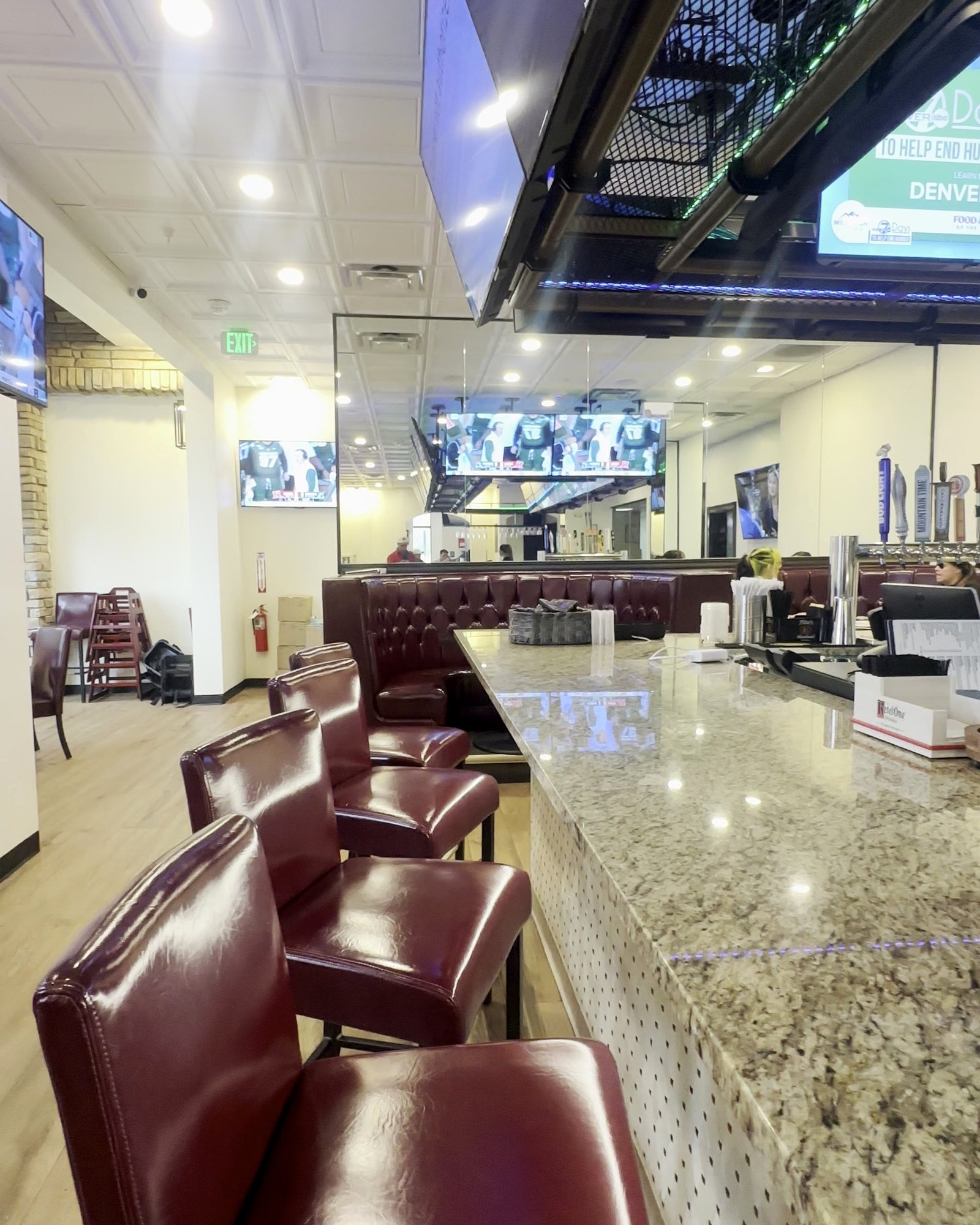 The long first-floor bar with stools, booths and a wall of TVs at Border Burger Sports Bar