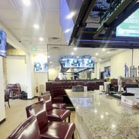 The long first-floor bar with stools, booths and a wall of TVs at Border Burger Sports Bar