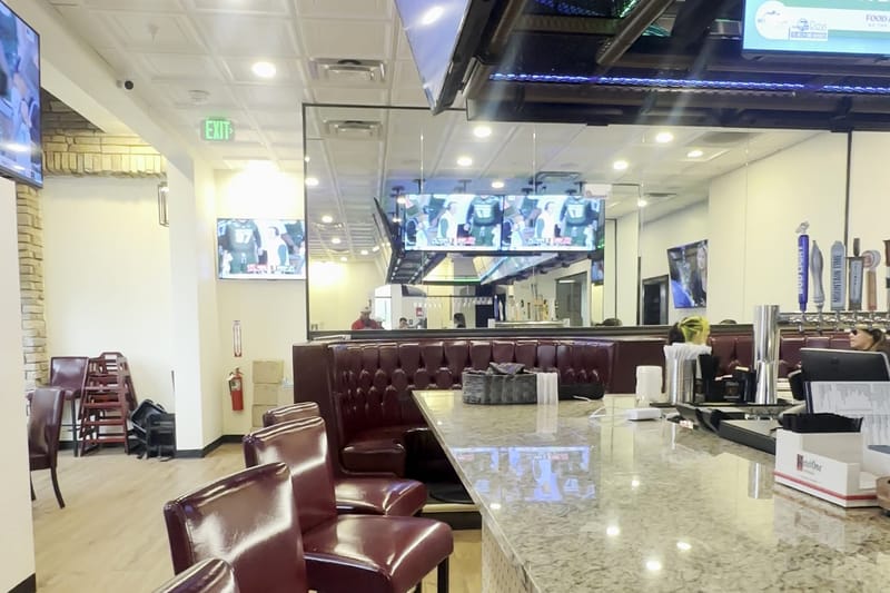 The long first-floor bar with stools, booths and a wall of TVs at Border Burger Sports Bar