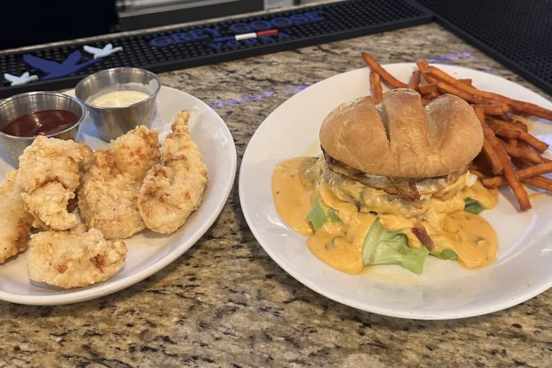 Red Bird chicken strips and the Miami burger with queso and sweet potato fries on the bar at Border Burger Sports Bar