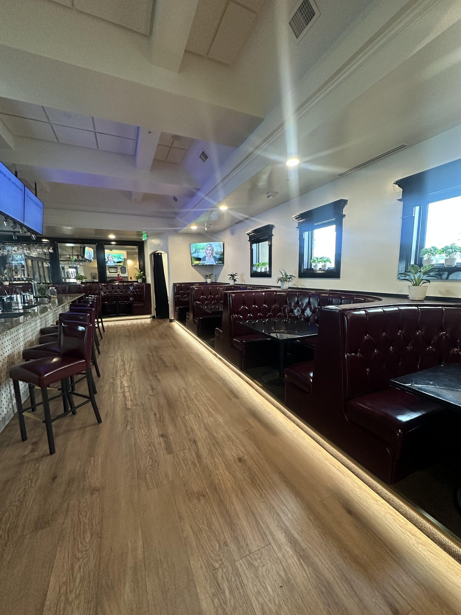 An upstairs bar with booths along the windows at Border Burger Sports Bar