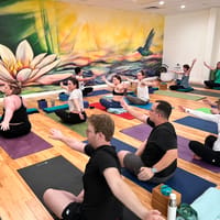 A yoga class with arms outstretched in front of a lotus-flower mural at Buka Yoga in downtown Castle Rock