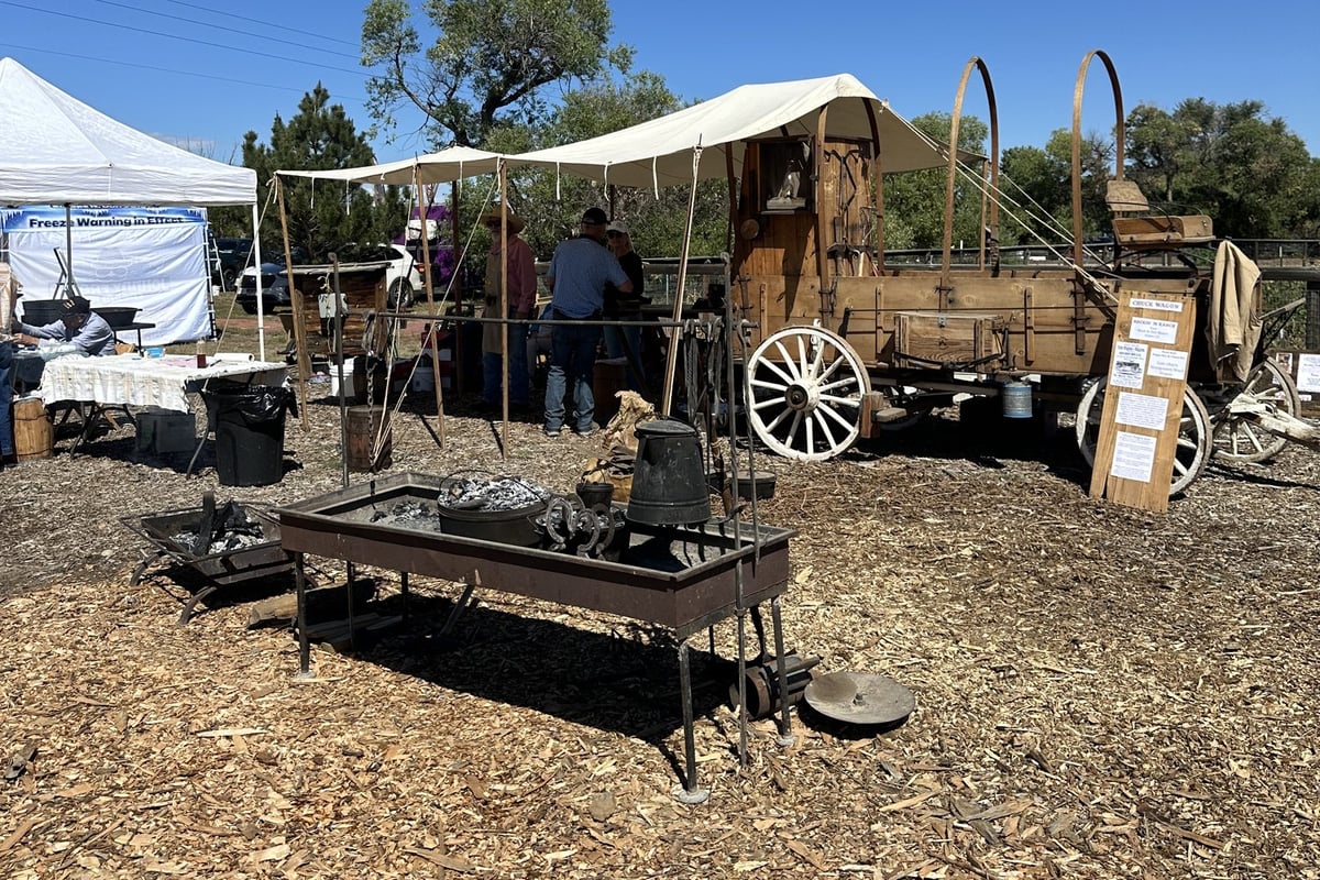 An old chuckwagon and fire pit under a canvas awning at CALF's Harvest Day