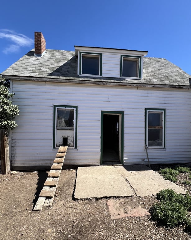 An old white farmhouse converted into a chicken coop with a wooden ramp at CALF's Lowell Ranch