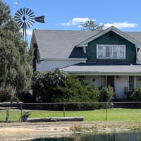 The Lowell ranch house and windmill behind the pond at CALF's Lowell Ranch in Castle Rock