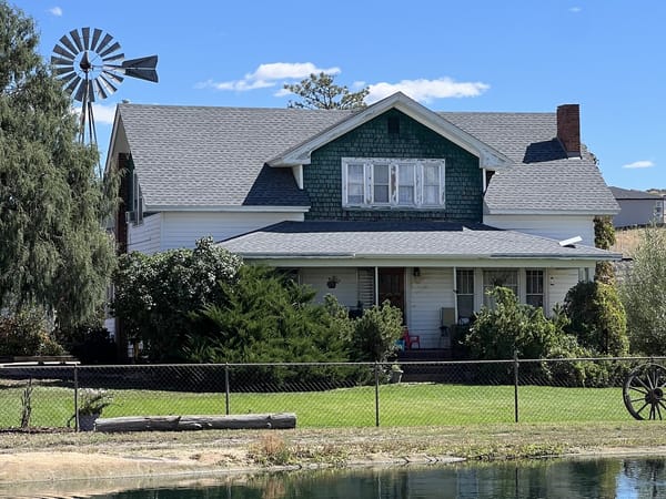 The Lowell ranch house and windmill behind the pond at CALF's Lowell Ranch in Castle Rock, Colorado